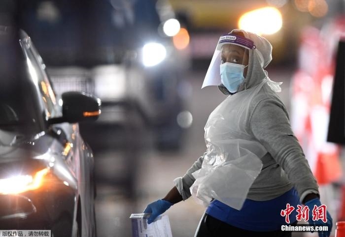 當(dāng)?shù)貢r間12月18日，英國政府公布的數(shù)據(jù)顯示，當(dāng)天英國新增奧密克戎毒株感染病例10059例。鑒于奧密克戎毒株感染病例激增，住院人數(shù)不斷上升，倫敦市長宣布倫敦進入“重大事故”狀態(tài)。圖為倫敦的一個免下車檢測中心，一名醫(yī)務(wù)工作者正準備對司機進行核酸檢測。