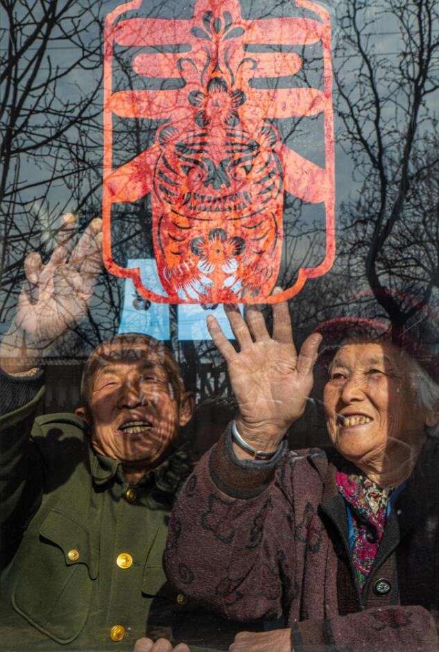 臘月里，霍州市師莊鄉(xiāng)馮南垣村村民師榮光(左)在災(zāi)后重建的新家里貼窗花。(霍州市委宣傳部供圖)