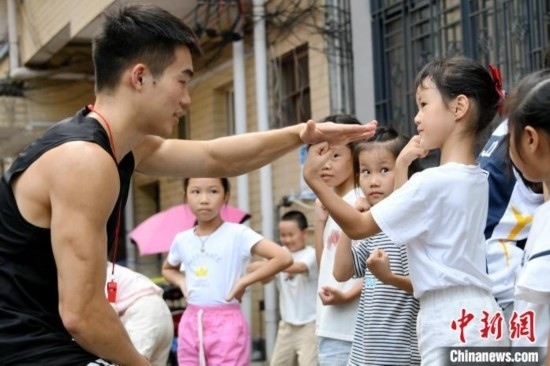 圖為大學生志愿者在組織孩子們參加體育健身活動。廖光福 攝