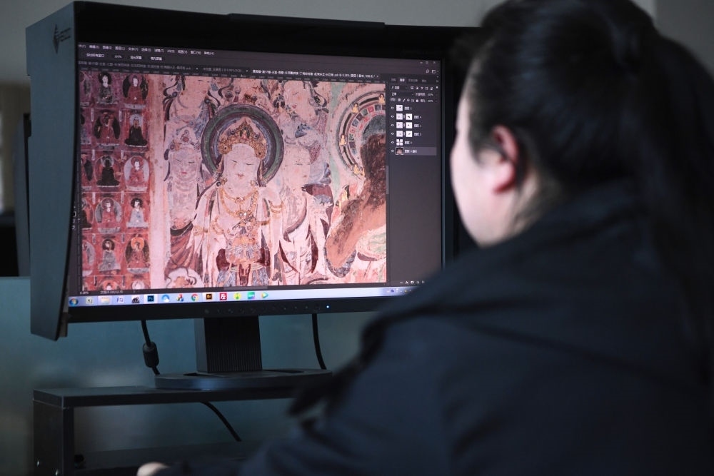 敦煌研究院文物數(shù)字化保護(hù)團(tuán)隊(duì)圖像處理人員年海麗在拼接壁畫圖像（2023年4月25日攝）。數(shù)字化探索為莫高窟的保護(hù)與傳承開辟了全新路徑，數(shù)字技術(shù)讓敦煌文物走出洞窟，跨出國門，走向“永久保存、永續(xù)利用”。新華社記者 陳斌 攝