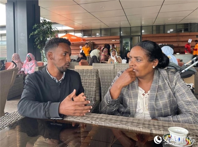 約漢斯（圖左）與德貝拉在友誼廣場咖啡廳交談。人民網(wǎng)記者 趙艷紅攝