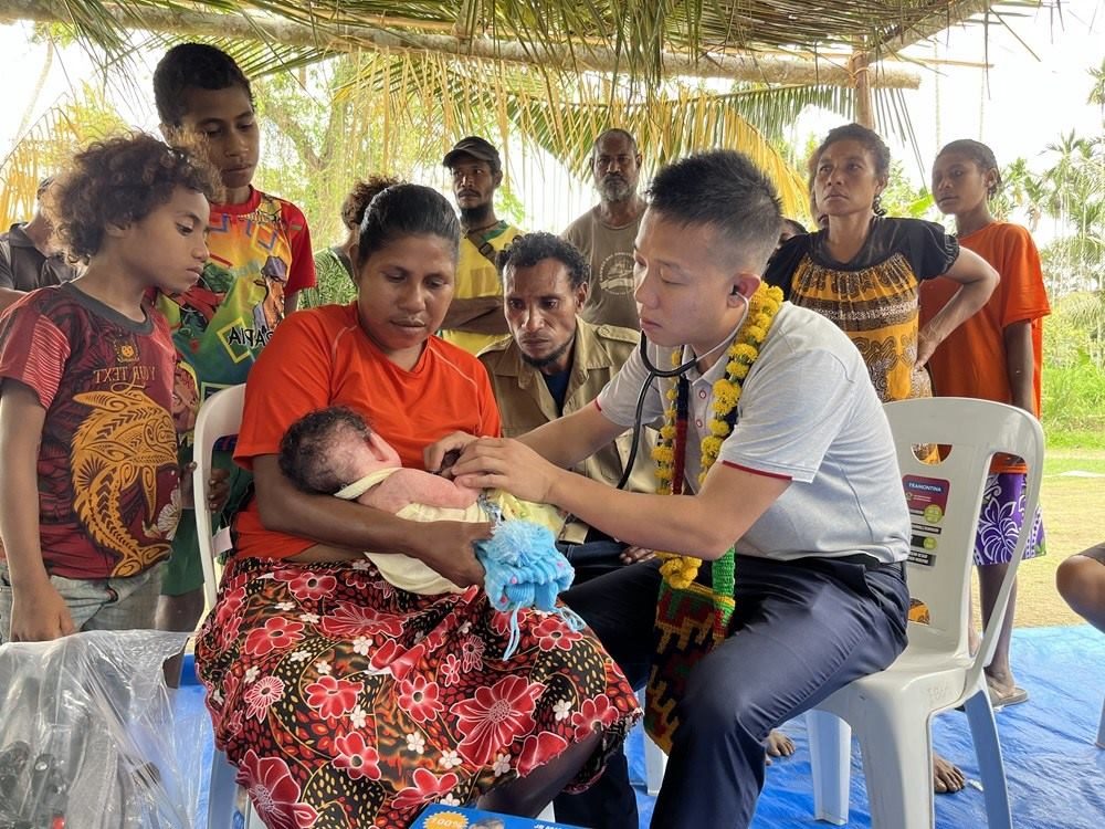 2023年8月5日，在巴布亞新幾內(nèi)亞中央省的一個村莊里，第12批援巴新中國醫(yī)療隊副隊長、新生兒科副主任醫(yī)師劉振球為當?shù)貗雰郝犜\檢查。新華社發(fā)（第12批援巴新中國醫(yī)療隊供圖）