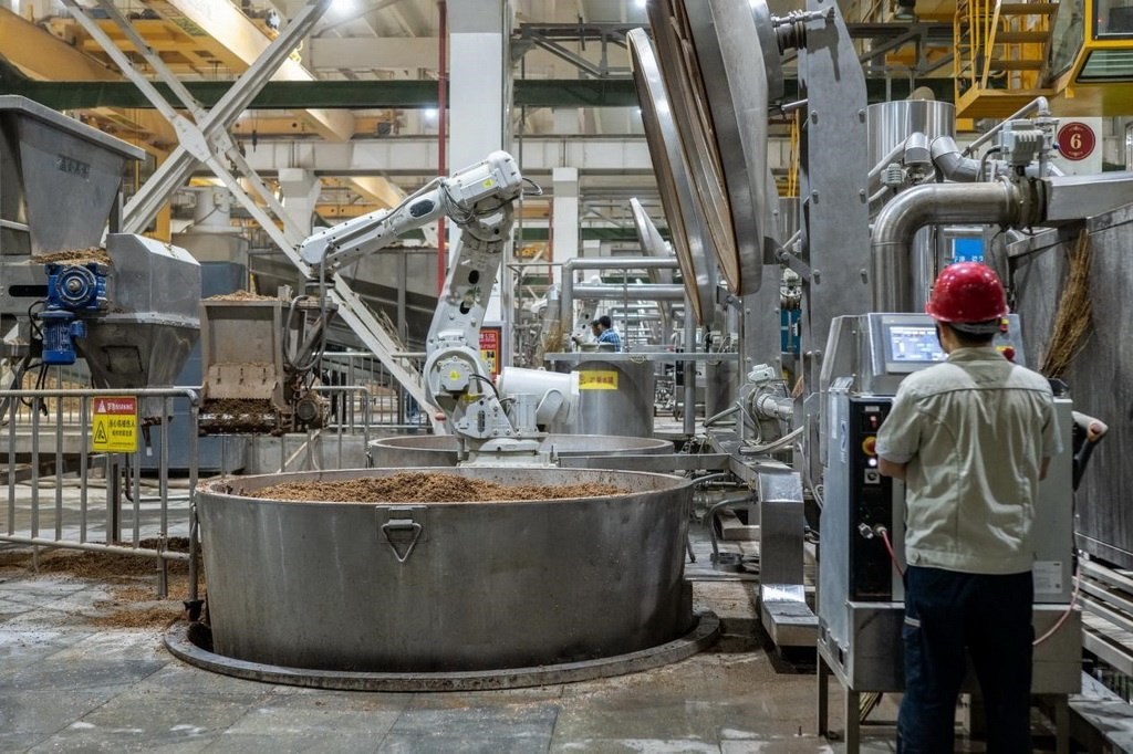 907車間里，機械臂正在撒料裝甑。嚴磊攝