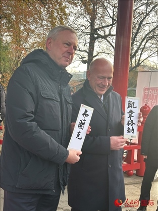 柏林市長韋格納（右）、動物園監(jiān)事會主席布魯克曼（左）手持中國文化中心工作人員現(xiàn)場手書的中文名字。人民網(wǎng)記者 徐馨攝