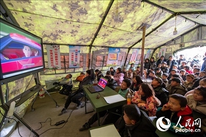 12月22日，在積石山縣大河家鎮(zhèn)大河村安置點(diǎn)，陸軍76集團(tuán)軍某旅搭建的“臨時(shí)學(xué)?！眱?nèi)，小朋友正在看動(dòng)畫片。人民網(wǎng)記者 翁奇羽攝