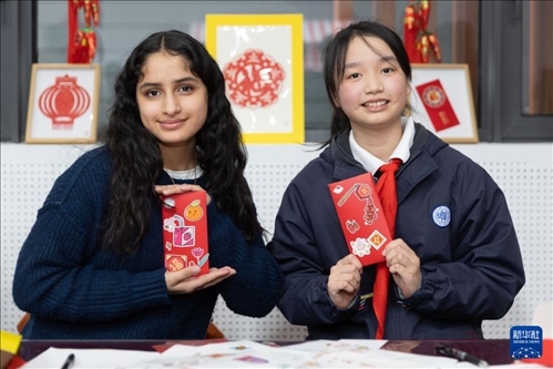 1月28日，美國馬斯卡廷中學學生（左）和復旦大學第二附屬學校學生展示互相送出的寫有寄語祝福的紅包。 新華社記者 王翔 攝