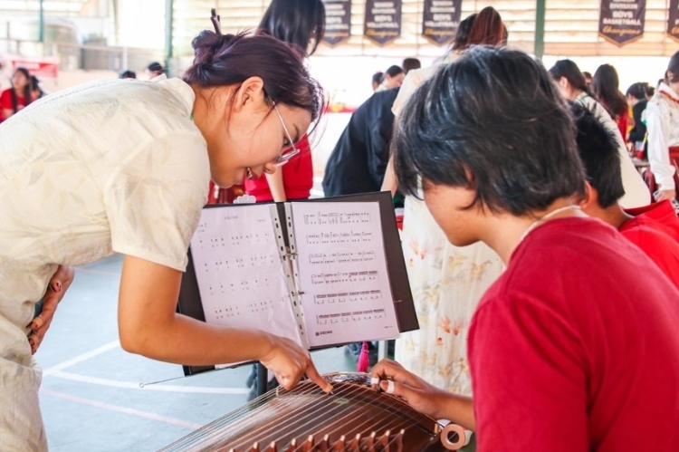 志愿者教師指導(dǎo)學(xué)生彈奏古箏?；顒又鬓k方供圖