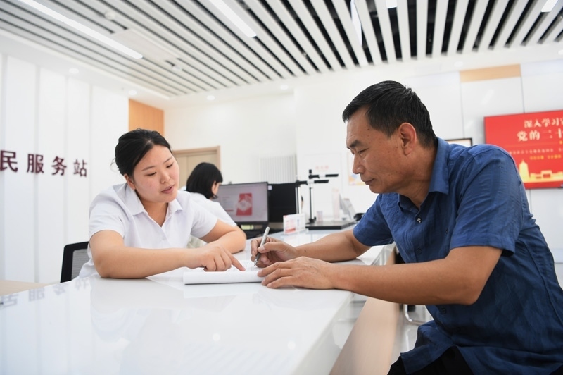 2023年5月23日，河北雄安新區(qū)容東片區(qū)南文營社區(qū)居民（右）在社區(qū)便民服務站辦理業(yè)務。
