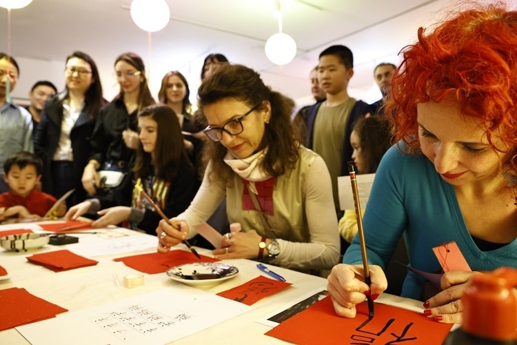 羅馬尼亞觀眾學(xué)習(xí)用毛筆寫“?！弊帧Ｖ袊?guó)文化中心供圖