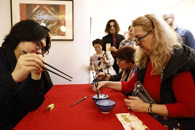 羅馬尼亞觀眾體驗(yàn)用筷子夾花生。中國(guó)文化中心供圖