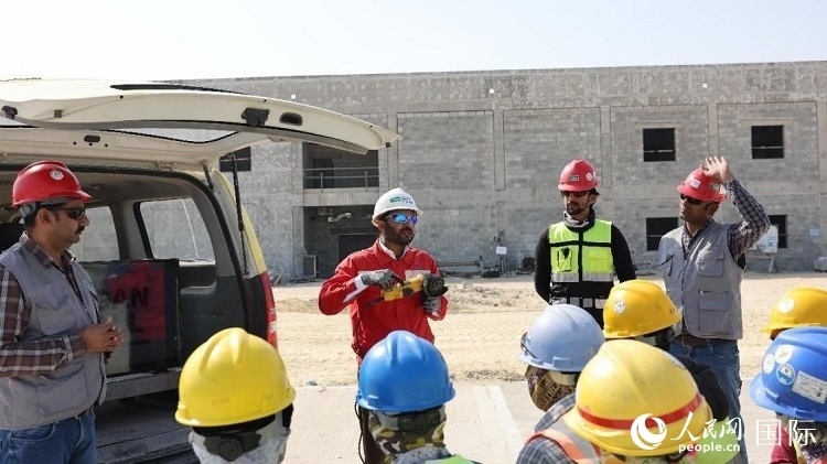 穆薩瓦爾(圖中紅衣人）現(xiàn)場演示工具操作規(guī)范。人民網(wǎng)記者 管克江攝