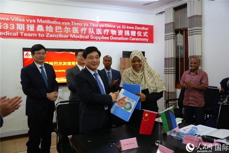 江蘇省蘇北人民醫(yī)院黨委書記束余聲與桑衛(wèi)生部首席秘書哈比巴交換捐贈書。中國援桑醫(yī)療隊供圖