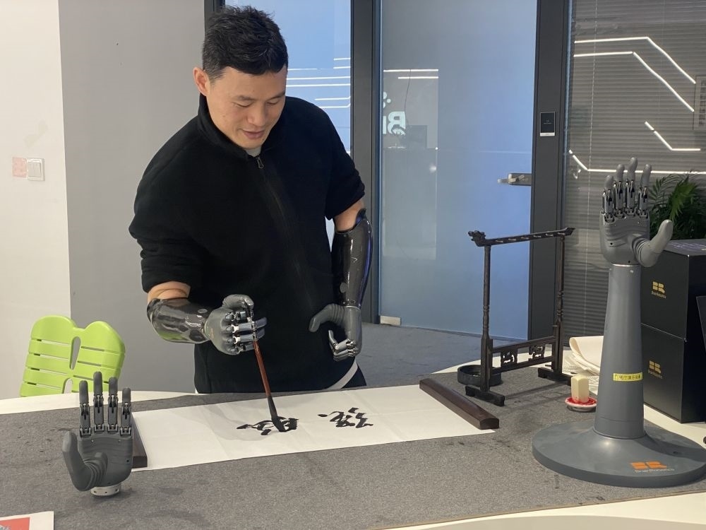 2024年3月29日，在浙江強(qiáng)腦科技有限公司展廳內(nèi)，失去雙手的產(chǎn)品體驗(yàn)官倪敏成依靠智能仿生手寫毛筆字。新華社記者 魏一駿 攝