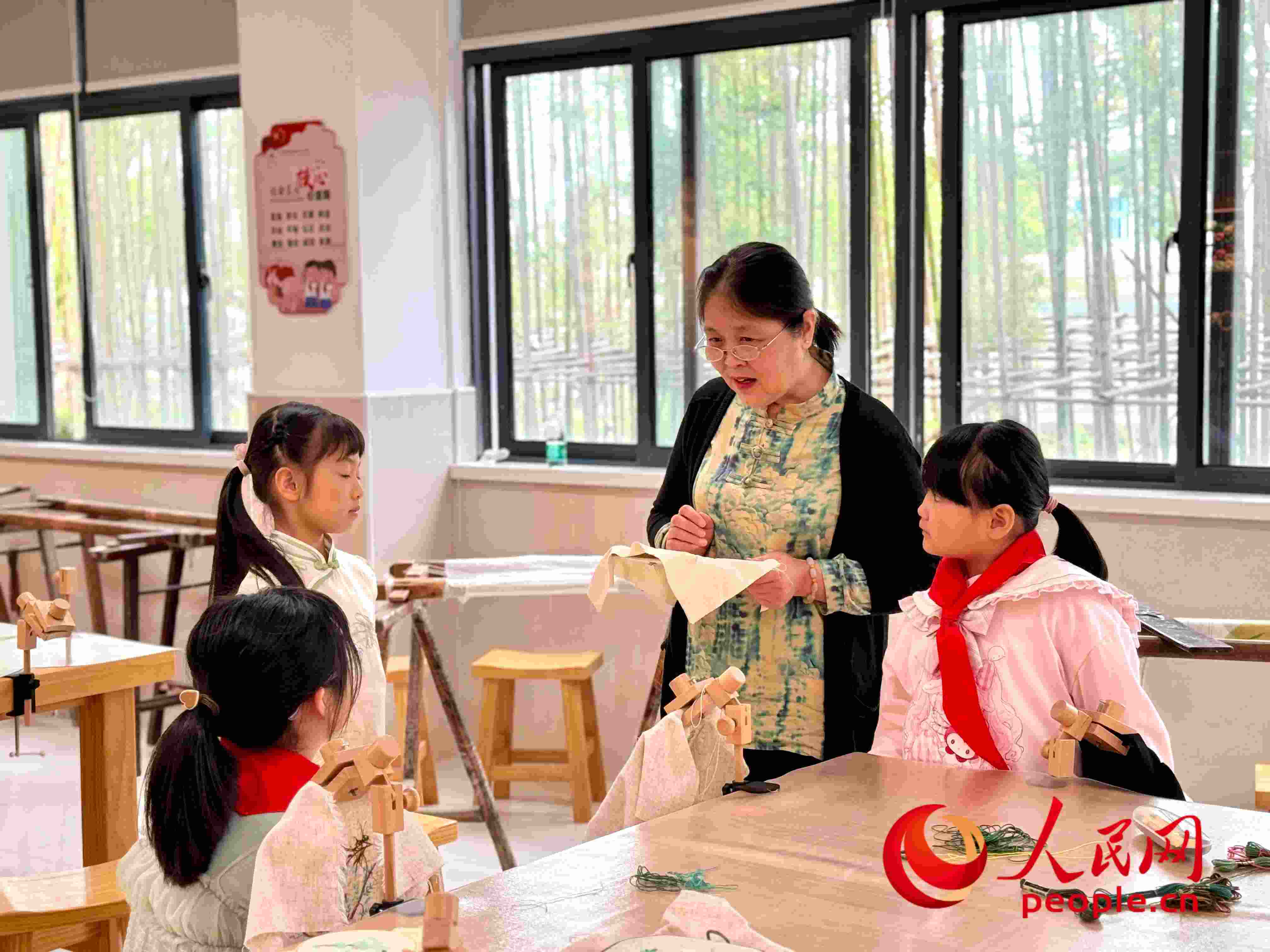 顧建珍（左三）在教孩子們刺繡知識。人民網(wǎng) 周靜圓攝