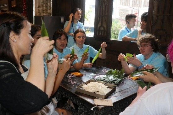 6月9日，美國青年代表在重慶永川松溉古鎮(zhèn)體驗(yàn)包粽子。新華社記者 周思宇 攝