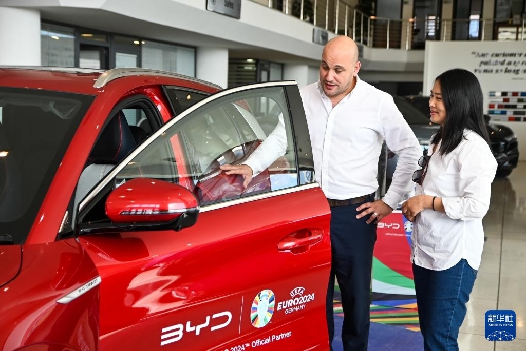 2024年5月29日，在馬耳他比爾基卡拉，馬耳他哈桑-扎米特汽車公司首席執(zhí)行官德古阿拉（左）介紹一輛比亞迪純電動汽車。新華社發(fā)（喬納森·博格 攝）