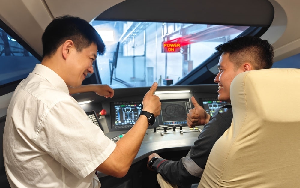 2023年8月25日，在印度尼西亞萬隆的雅萬高鐵德卡魯爾動(dòng)車所內(nèi)，中國師傅穆振（左）向印尼火車司機(jī)塞蒂亞萬講解動(dòng)車組出庫前的上電作業(yè)。新華社記者 徐欽 攝