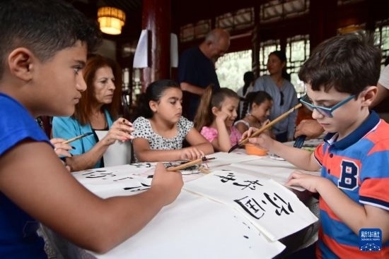 7月4日，在馬耳他桑塔露琪亞市的中國(guó)古典園林“靜園”，人們體驗(yàn)中國(guó)書法。新華社發(fā)（喬納森·博格 攝）