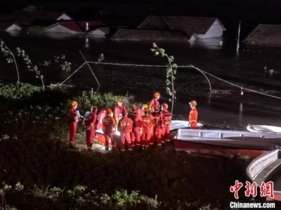  7月6日凌晨3時(shí)，在湖南岳陽(yáng)華容縣團(tuán)洲垸洞庭湖一線堤防，救援人員剛剛完成一次救援任務(wù)，遠(yuǎn)處是被淹的民房。中新社記者 白祖偕 攝