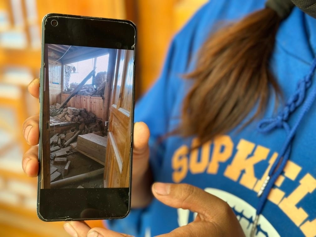 圖為7月17日拉毛東智在手機上找出地震后房屋受損的照片。新華社記者 張子琪 攝