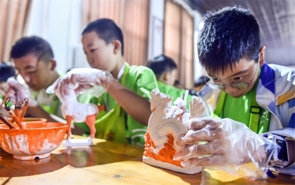 小朋友們?cè)诼尻?yáng)市孟津區(qū)朝陽(yáng)鎮(zhèn)南石山村體驗(yàn)唐三彩素胎施釉技藝。圖片來(lái)源:視覺中國(guó)