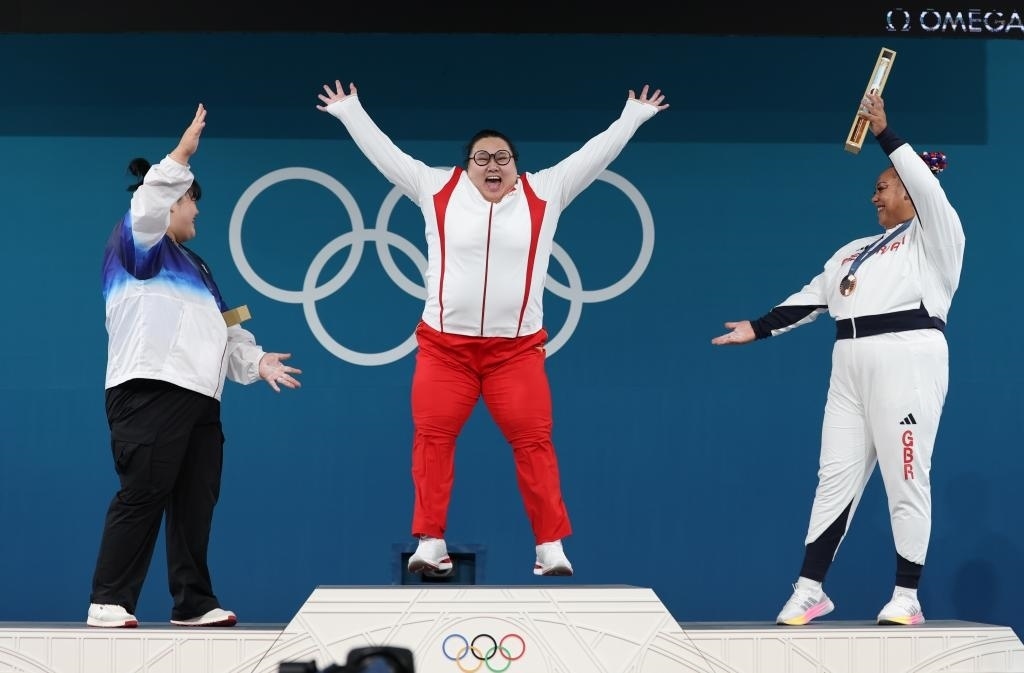 中國(guó)選手李雯雯（中）在巴黎奧運(yùn)會(huì)舉重女子81公斤以上級(jí)頒獎(jiǎng)儀式中登上領(lǐng)獎(jiǎng)臺(tái)（2024年8月11日攝）。新華社記者 楊磊 攝