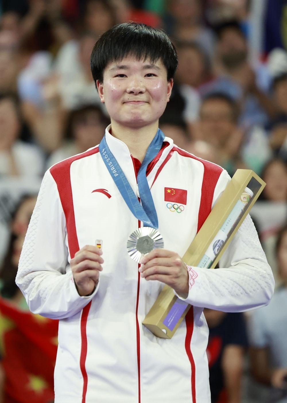 巴黎奧運(yùn)會(huì)羽毛球女子單打亞軍、中國(guó)選手何冰嬌在頒獎(jiǎng)儀式上一手握著銀牌，一手握著西班牙奧委會(huì)徽章（2024年8月5日攝）。新華社記者 任正來 攝