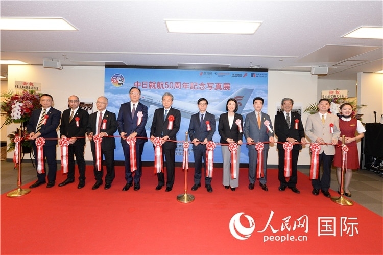 與會(huì)嘉賓共同為中日通航50周年紀(jì)念圖片展開幕剪彩。馮學(xué)敏攝