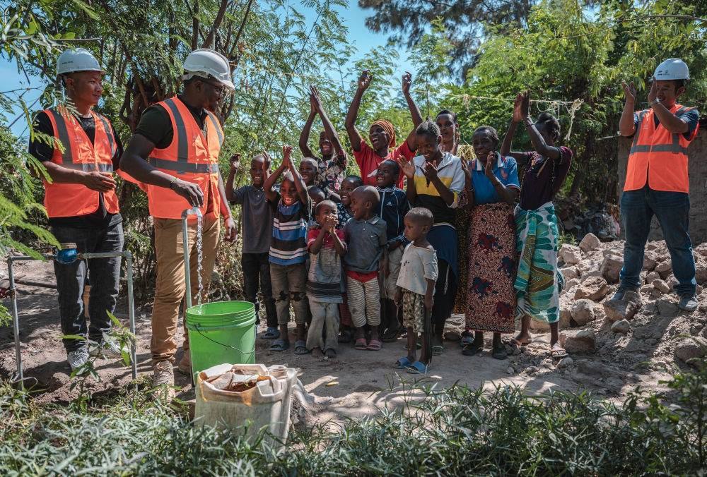 2023年6月13日，在坦桑尼亞姆萬扎省米松圭，工作人員接通水管后贏得當(dāng)?shù)鼐用窆恼茪g呼。新華社記者 王冠森 攝