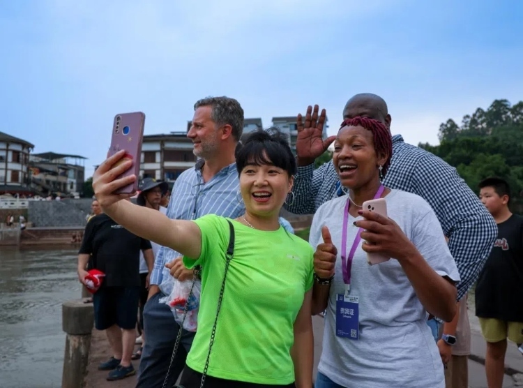 2024“一帶一路”媒體合作論壇聯合采訪調研行成員在樂山蘇稽古鎮(zhèn)與游客合影留念。本報記者 伊霄攝