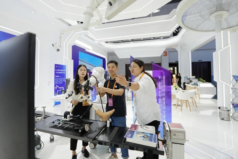 9月11日，一位媒體記者（中）在2024年服貿(mào)會國家會議中心會場體驗北京納通科技集團有限公司的膝關(guān)節(jié)置換手術(shù)機器人。新華社記者鞠煥宗 攝