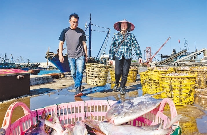 許小斌(左)和漁民一起搬運海鮮。本報記者 付 文攝