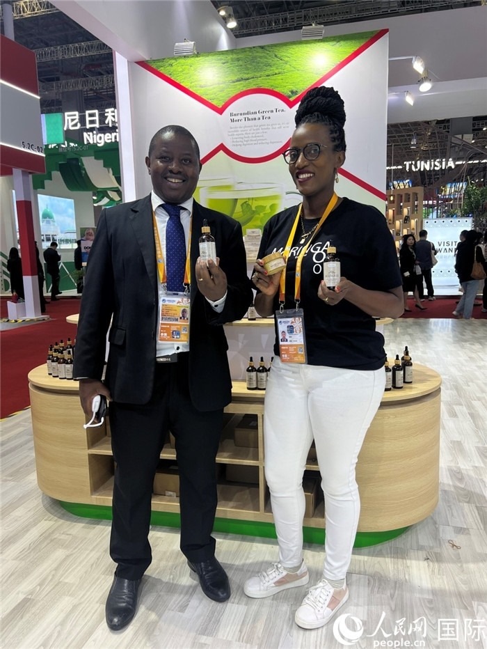 6月6日，布隆迪駐華大使館一等參贊布利馬索·阿爾弗雷德 (左，Bulimaso Alfred) 和參展商卡馬里扎·埃斯特拉 (Kamariza Estella) 在第七屆中國(guó)國(guó)際進(jìn)口博覽會(huì)布隆迪館展示當(dāng)?shù)厣a(chǎn)的辣木油。（人民網(wǎng) 艾里士 攝）