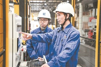 在廣西柳工機(jī)械股份有限公司生產(chǎn)車(chē)間內(nèi)，一名高級(jí)技師（右）給徒弟講解數(shù)控設(shè)備操作細(xì)節(jié)。新華社記者 曹祎銘攝