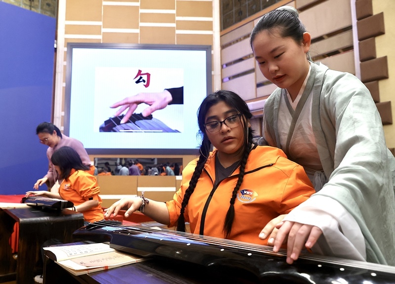 2024年3月20日，美國華盛頓州中學(xué)生代表團(tuán)北京大學(xué)交流活動(dòng)在北京大學(xué)英杰交流中心舉行。圖為來自華盛頓州的中學(xué)生體驗(yàn)古琴。