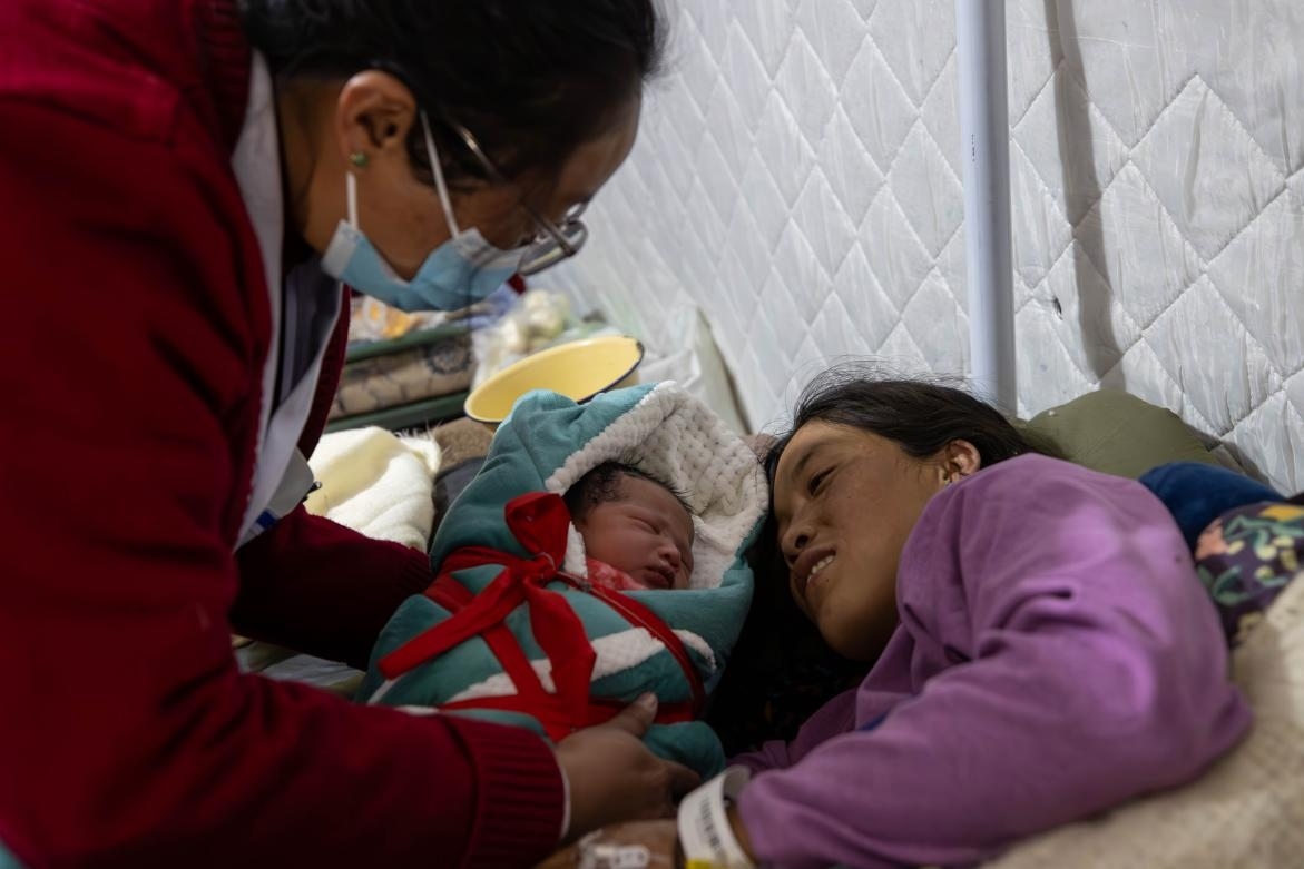 1月10日，定日縣中心醫(yī)院的婦產(chǎn)科醫(yī)生悉心照看一位母親和她懷里的新生兒。人民日?qǐng)?bào)記者張武軍攝