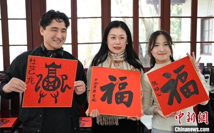 1月20日，外籍留學生和西泠印社社員李硯(中)展示各自創(chuàng)作的福貼。當日，來自巴西、馬來西亞、加納、哈薩克斯坦的外籍留學生在浙江杭州西泠印社體驗福貼、春聯(lián)和篆刻，感受古老的中國傳統(tǒng)文化。中新社記者 王剛 攝