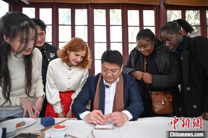 1月20日，篆刻家王臻向外籍留學生展示篆刻印章。當日，來自巴西、馬來西亞、加納、哈薩克斯坦的外籍留學生在浙江杭州西泠印社體驗福貼、春聯(lián)和篆刻，感受古老的中國傳統(tǒng)文化。中新社記者 王剛 攝