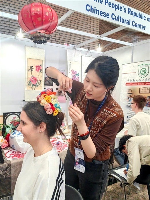 展覽正值羅馬尼亞迎春花節(jié)，國際中文教師志愿者潘婧穎向游客們介紹了國家非物質(zhì)文化遺產(chǎn)——福建泉州的簪花文化。布加勒斯特大學孔子學院供圖。