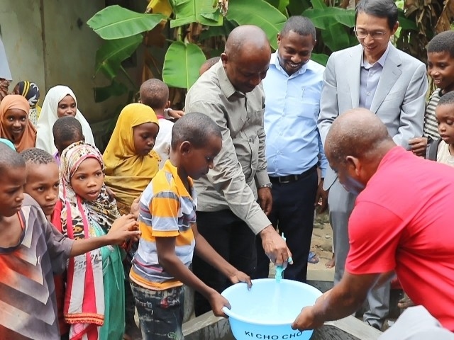 在日前舉行的安全供水工程揭牌儀式上，當?shù)匦∨笥言诠┧c接水。 施亮攝
