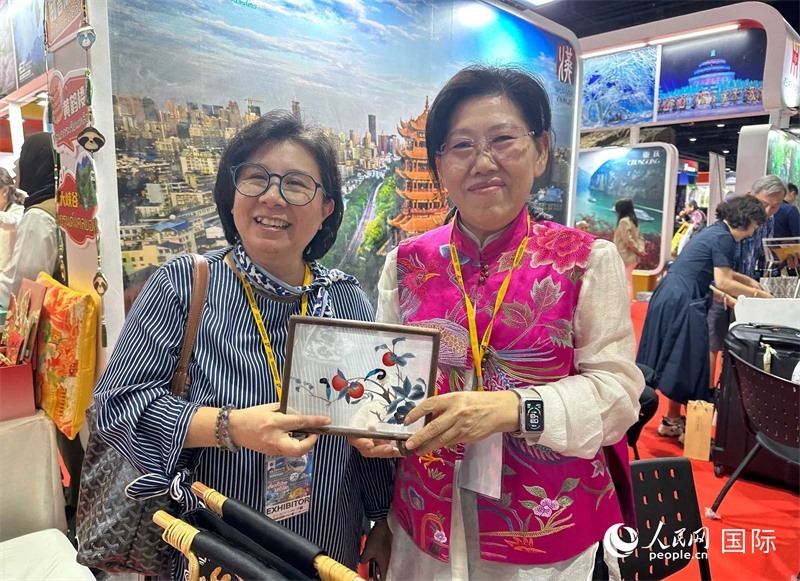 中國“大冶刺繡”傳承人劉小紅（右）參加泰國國際旅游展，向觀眾介紹中國非遺刺繡針法。人民網(wǎng)記者 簡承淵攝