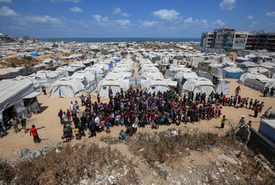 5月28日，人們?cè)诩由吵俏鞑康纳程犭y民營等待領(lǐng)取救助食物。新華社發(fā)（里澤克·阿卜杜勒賈瓦德攝）